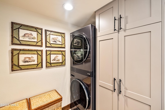 clothes washing area featuring cabinets and stacked washer and clothes dryer