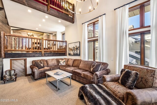 living room with a towering ceiling, carpet floors, and a notable chandelier