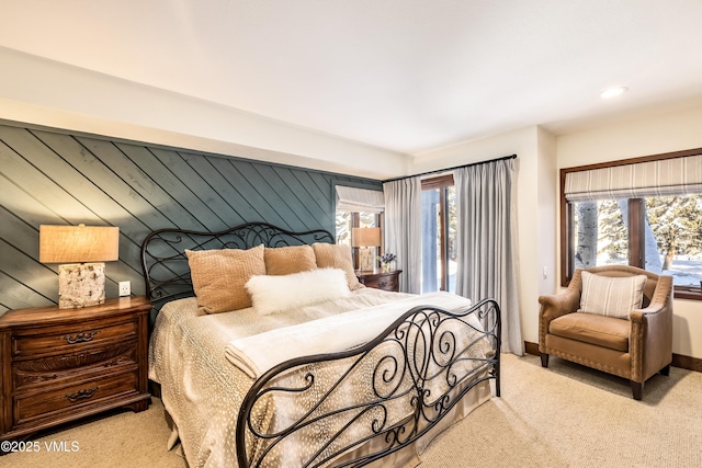 bedroom with multiple windows, light carpet, and wooden walls