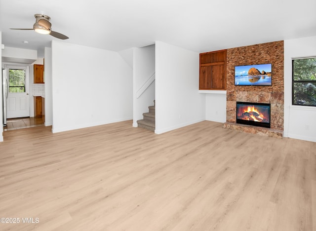 2403 Draw Spur Unit 2, Avon, CO 81620 - unfurnished living room with light wood-style floors, ceiling fan, a fireplace, stairway, and plenty of natural light