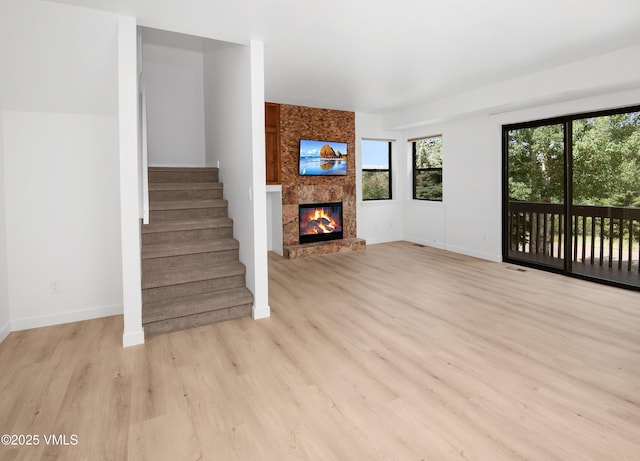 2403 Draw Spur Unit 2, Avon, CO 81620 - unfurnished living room with a large fireplace, light wood-type flooring, and stairway