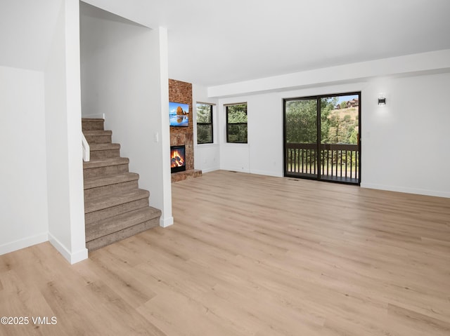 2403 Draw Spur Unit 2, Avon, CO 81620 - unfurnished living room featuring light wood-style floors, a fireplace, and stairs