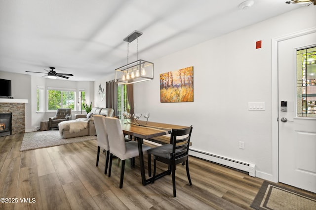 601 Crazy Horse Cir Unit 601, Edwards, CO 81632 - dining area featuring a baseboard radiator, wood finished floors, a stone fireplace, and a ceiling fan