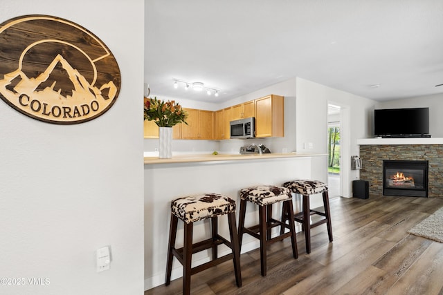601 Crazy Horse Cir Unit 601, Edwards, CO 81632 - kitchen with stainless steel microwave, dark wood finished floors, a breakfast bar, a fireplace, and light brown cabinets