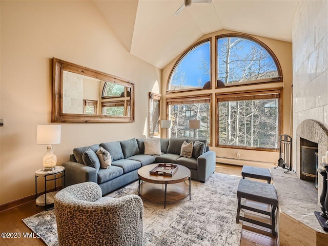 living room featuring baseboards, a tile fireplace, wood finished floors, high vaulted ceiling, and a baseboard radiator