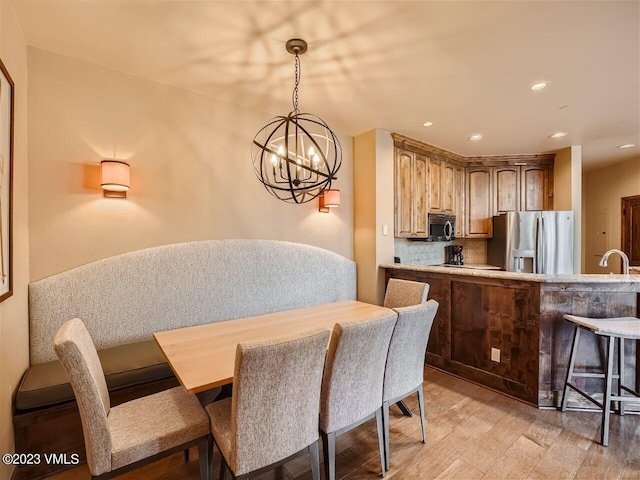 dining space featuring light wood finished floors, a chandelier, and recessed lighting