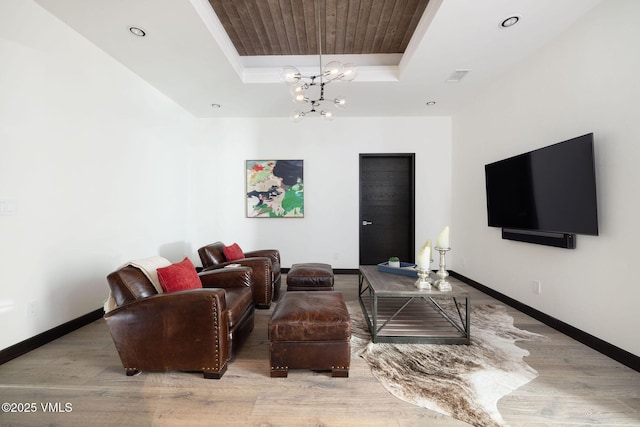 living room featuring an inviting chandelier, wood ceiling, a tray ceiling, and light wood-type flooring