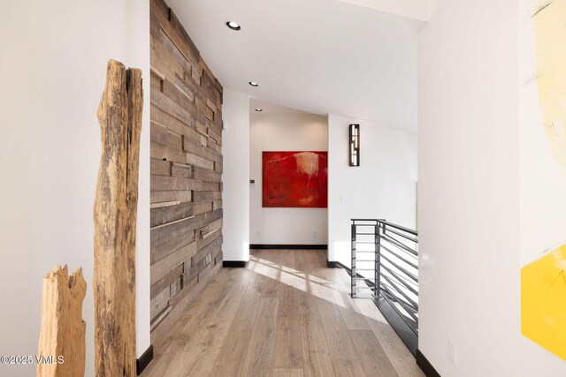 corridor with wooden walls and light hardwood / wood-style floors