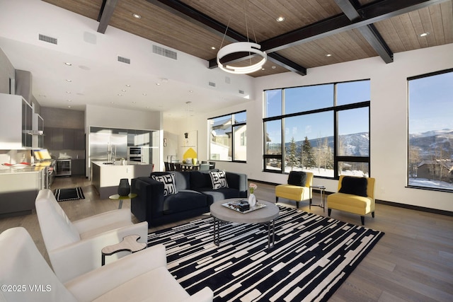 living room with a mountain view, beam ceiling, wood-type flooring, and wooden ceiling