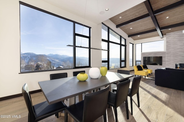 dining area with wooden ceiling, beam ceiling, a mountain view, and light wood-type flooring