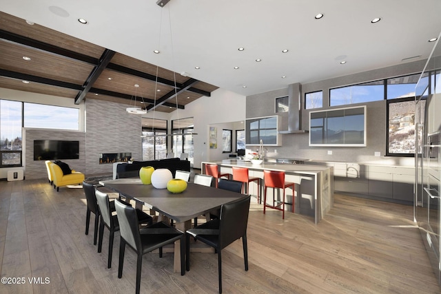 dining space featuring a towering ceiling, light hardwood / wood-style flooring, and beamed ceiling