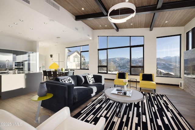 living room with beam ceiling, a mountain view, wood ceiling, and hardwood / wood-style floors