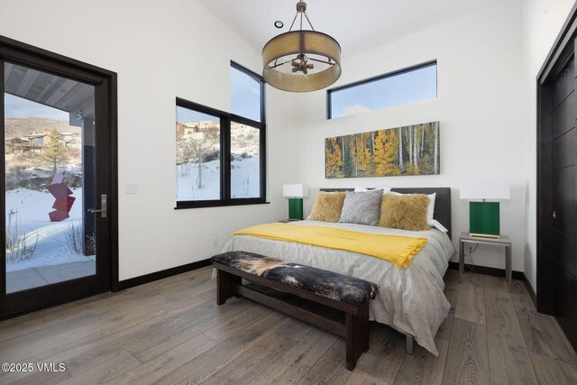 bedroom featuring hardwood / wood-style flooring, a high ceiling, and access to exterior