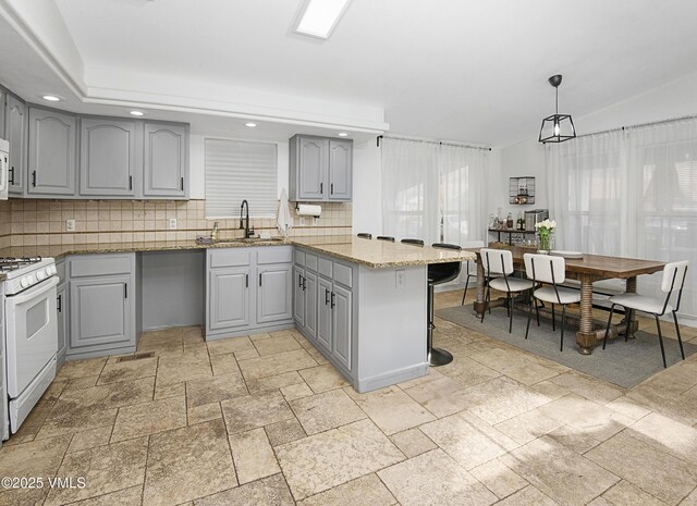 kitchen featuring gray cabinets, sink, decorative backsplash, hanging light fixtures, and white appliances