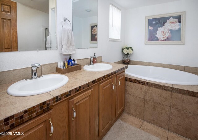 bathroom with a relaxing tiled tub, vanity, and tile patterned flooring