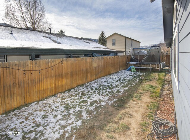 yard covered in snow with a trampoline