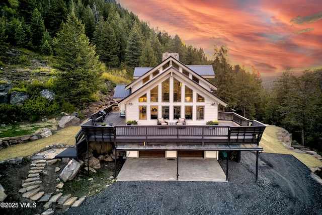 2980 Salt Creek Rd, Eagle, CO 81631 - back of property featuring a deck, gravel driveway, a patio area, a chimney, and a forest view