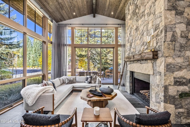 sunroom / solarium with wood ceiling, a stone fireplace, and lofted ceiling with beams