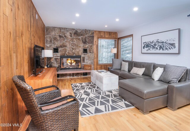 living room featuring a stone fireplace and light hardwood / wood-style floors