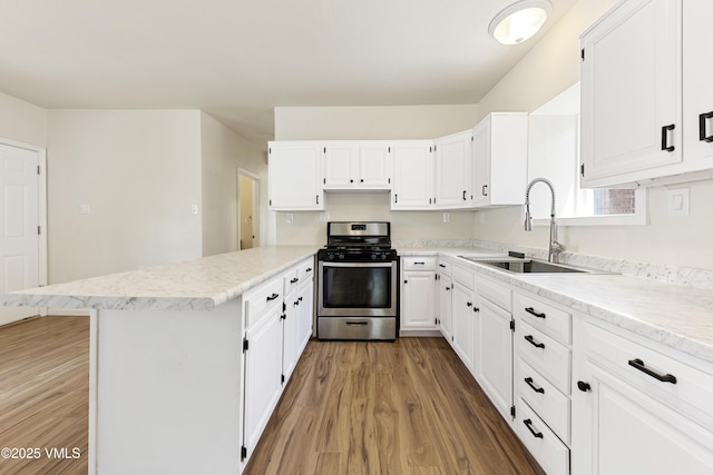 423 Second St, Gypsum, CO 81637 - kitchen with stainless steel range with gas stovetop, a sink, a peninsula, light wood finished floors, and white cabinetry