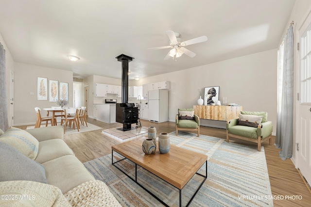 423 Second St, Gypsum, CO 81637 - living area featuring a wood stove, light wood-style flooring, ceiling fan, and baseboards