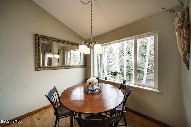 dining area featuring dark wood-type flooring, baseboards, a textured wall, and lofted ceiling