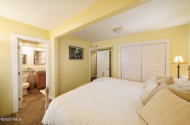 carpeted bedroom with a sink, a closet, ensuite bath, and visible vents