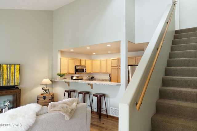 living room featuring visible vents, stairway, light wood finished floors, a high ceiling, and recessed lighting