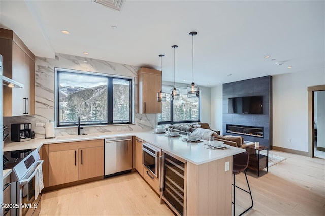 42 Riverfront Ln Unit 205, Avon, CO 81620 - kitchen with stainless steel appliances, beverage cooler, a peninsula, light brown cabinets, and light countertops
