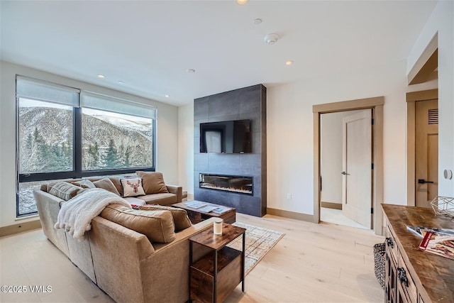 42 Riverfront Ln Unit 205, Avon, CO 81620 - living area featuring a tile fireplace, light wood-type flooring, and recessed lighting