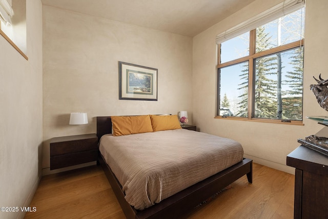 bedroom with multiple windows and light hardwood / wood-style flooring