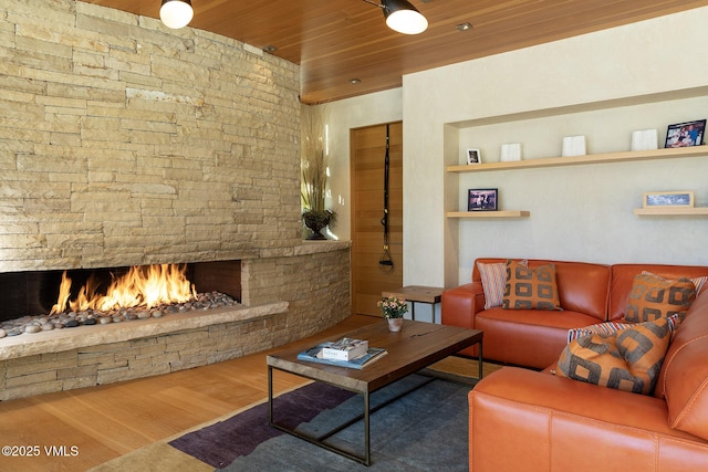 living room with wood ceiling, wood-type flooring, and a stone fireplace