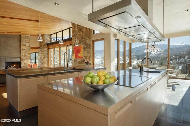 kitchen featuring pendant lighting, sink, island exhaust hood, a kitchen island with sink, and a mountain view