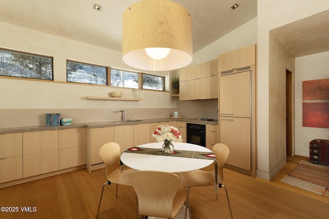 kitchen featuring tasteful backsplash, sink, light hardwood / wood-style floors, and black appliances