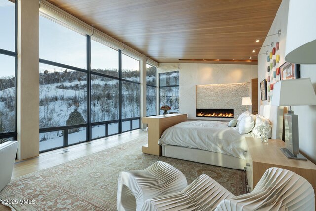 bedroom featuring floor to ceiling windows, wood ceiling, and light wood-type flooring