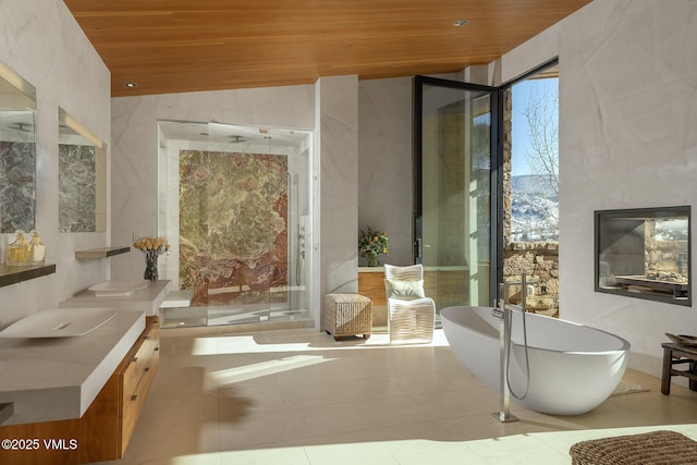 bathroom with lofted ceiling, wood ceiling, tile patterned flooring, vanity, and a bathing tub