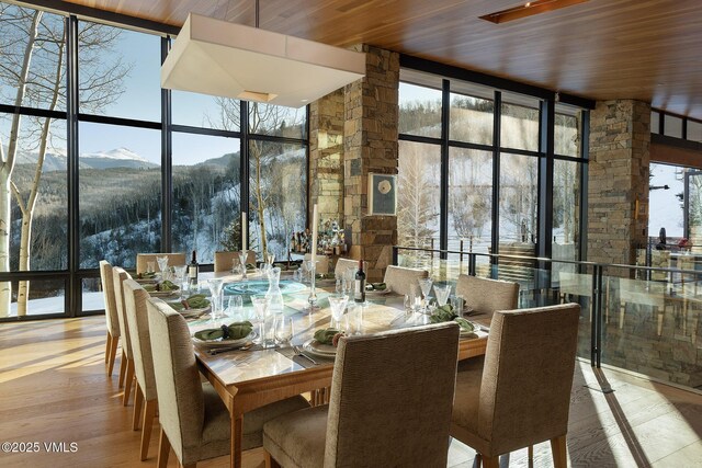 dining space featuring a mountain view, wood ceiling, hardwood / wood-style floors, and expansive windows