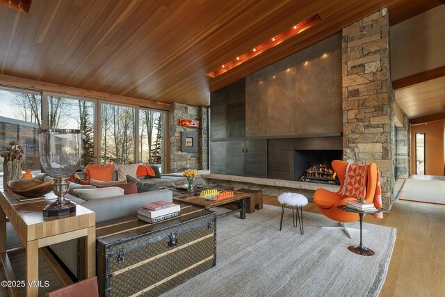 interior space with high vaulted ceiling, a stone fireplace, a wealth of natural light, and wood ceiling