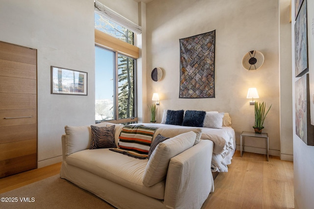 bedroom featuring multiple windows, a high ceiling, and light hardwood / wood-style flooring