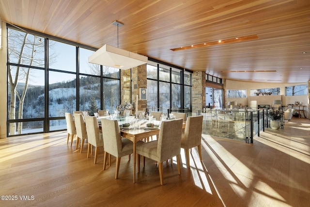 dining area featuring wood ceiling, a wall of windows, light hardwood / wood-style floors, and plenty of natural light