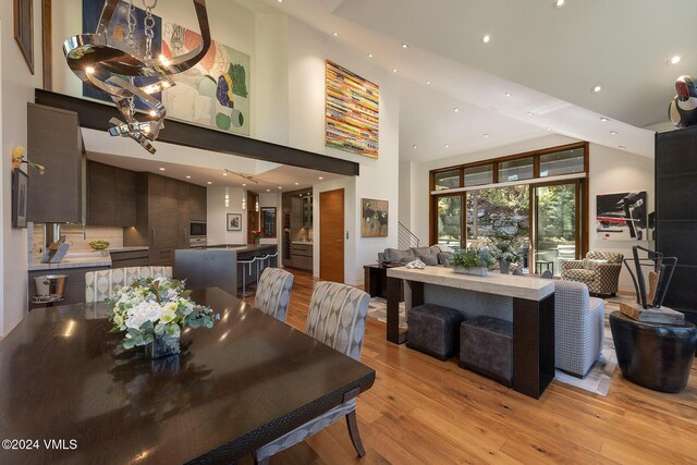 dining space featuring recessed lighting, a towering ceiling, stairs, light wood-type flooring, and an inviting chandelier