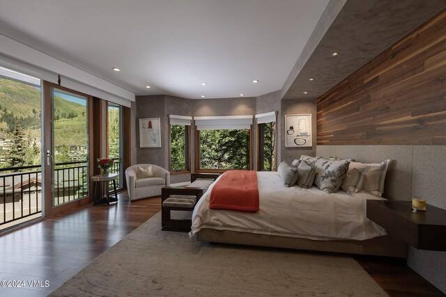 bedroom featuring access to exterior, wood walls, wood finished floors, and recessed lighting