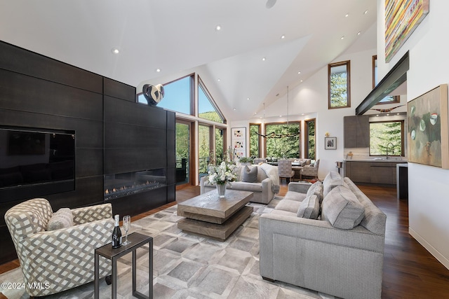 living room featuring light wood finished floors, high vaulted ceiling, a large fireplace, and recessed lighting