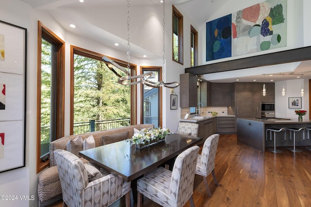 dining space with high vaulted ceiling, an inviting chandelier, wood finished floors, and recessed lighting