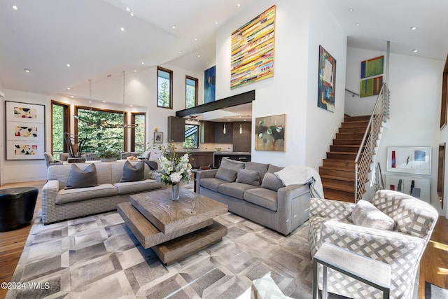 living area with light wood-type flooring, recessed lighting, stairway, and a high ceiling