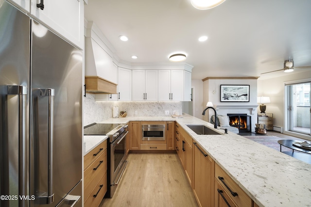 180 Offerson Rd Unit 2, Beaver Creek, CO 81620 - kitchen with premium appliances, a sink, light wood-style floors, a warm lit fireplace, and light stone countertops