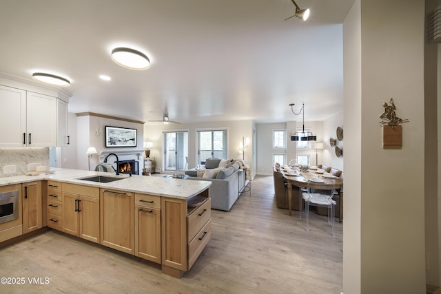 180 Offerson Rd Unit 2, Beaver Creek, CO 81620 - kitchen with a sink, light wood-style floors, a peninsula, and a warm lit fireplace