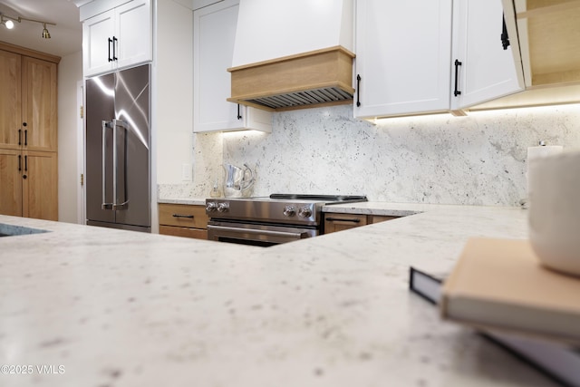 180 Offerson Rd Unit 2, Beaver Creek, CO 81620 - kitchen featuring stainless steel appliances, custom exhaust hood, backsplash, light stone counters, and white cabinets