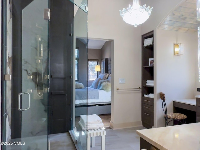 ensuite bathroom featuring a stall shower, baseboards, ensuite bath, vanity, and a notable chandelier