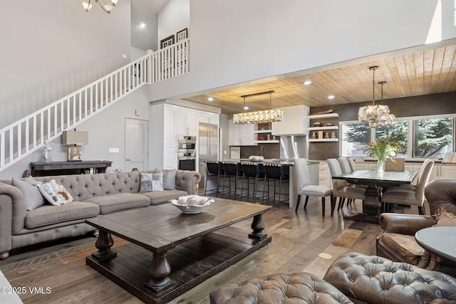 living room with stairway, wooden ceiling, wood finished floors, and a notable chandelier